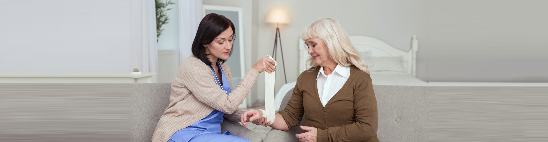 nurse applying a bandage to arm senior woman
